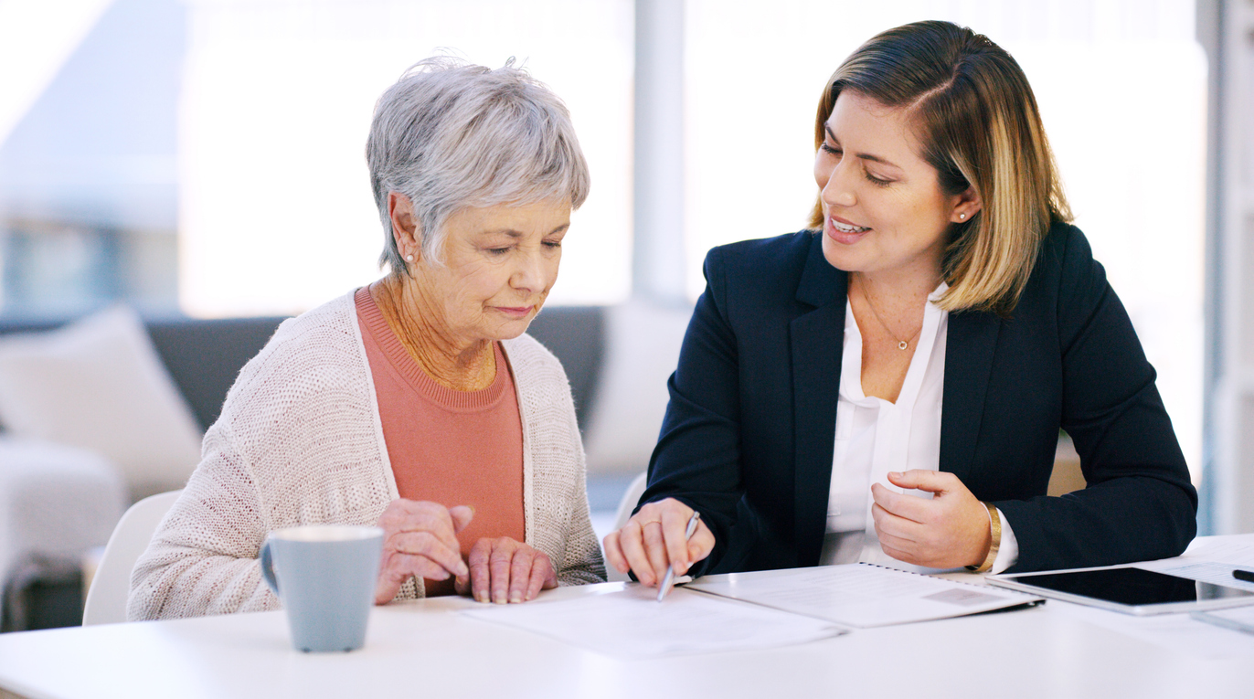 An older woman reviewing paperwork with a professional in a navy blazer